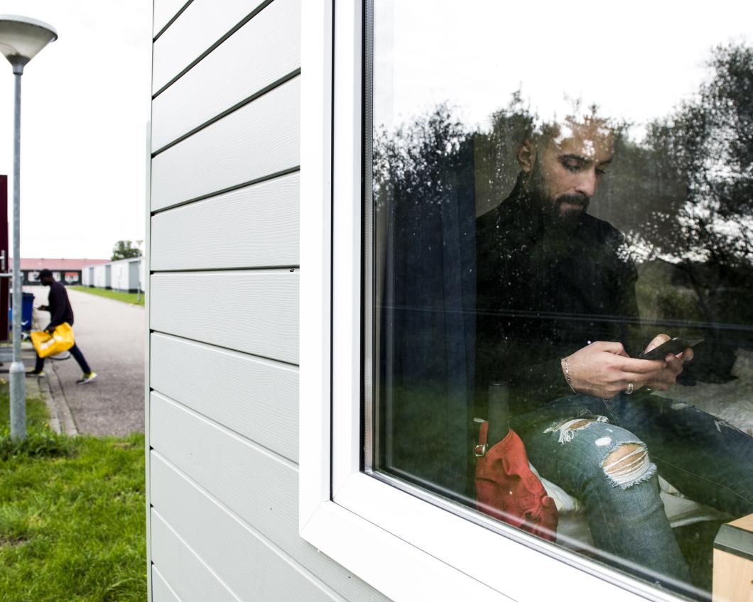 Foto van Masaoud achter het raam van zijn stacaravan